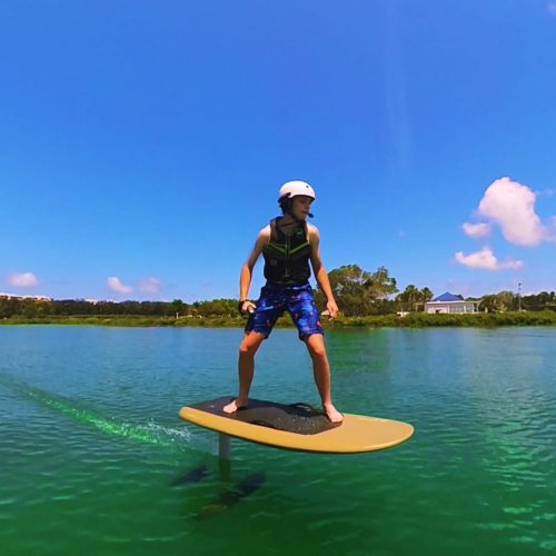 Teenager in a helmet and lifejacket gliding over Sarasota Bay on a Fliteboard