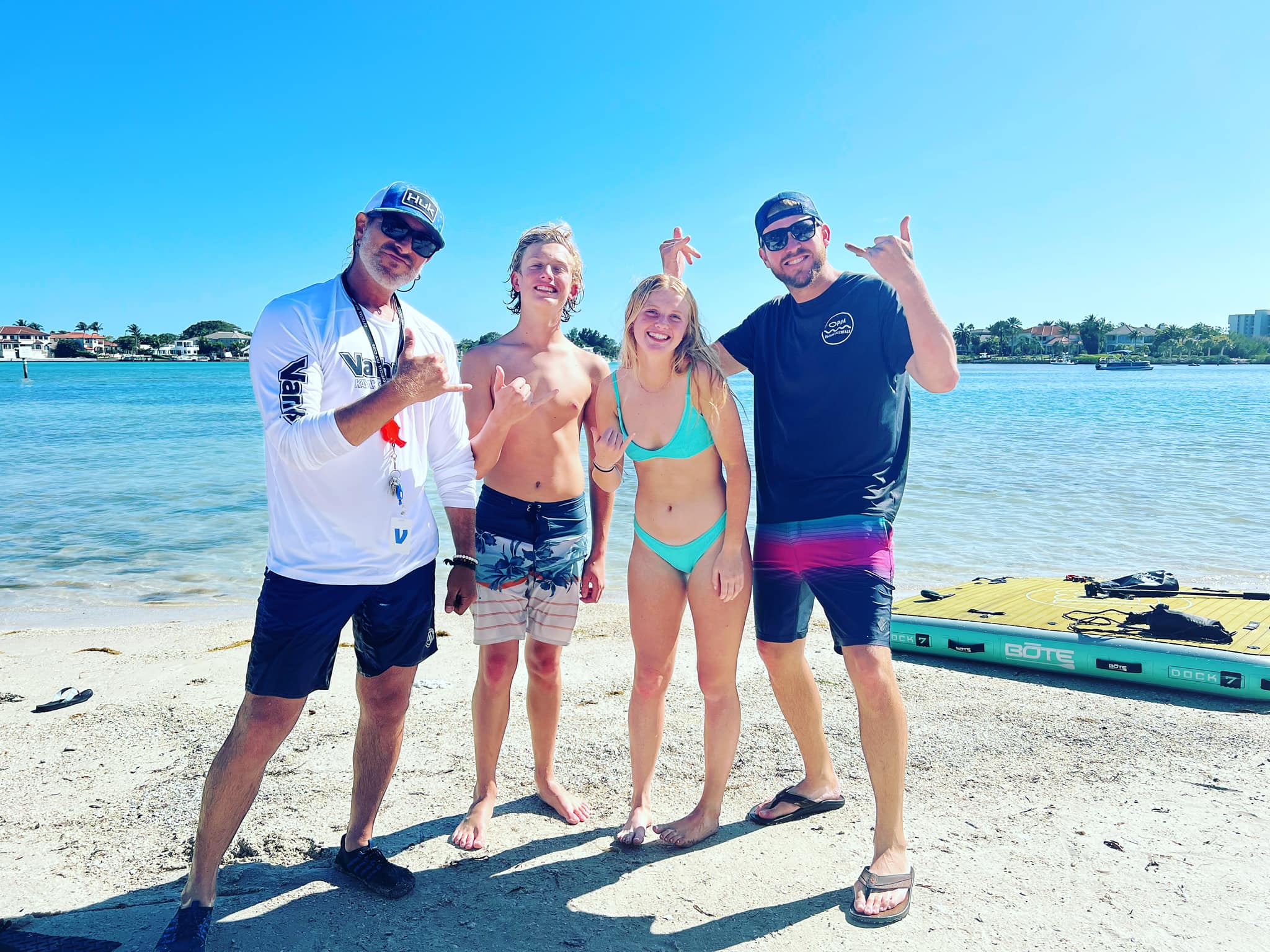 Opua Adventures Instructors posing on the beach with a young man and woman after a successful lesson